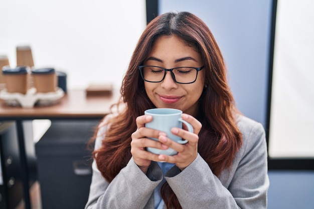 Junge hispanische Frau Geschäftsangestellter trinkt Kaffee im Büro