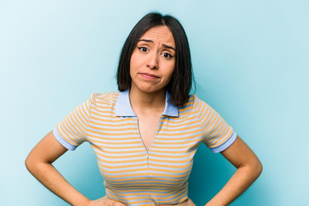 Foto junge hispanische frau isoliert auf blauem hintergrund verwirrt fühlt sich zweifelhaft und unsicher