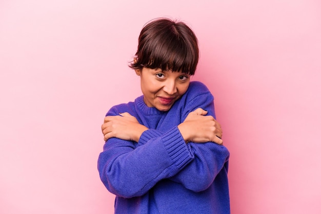 Junge hispanische Frau isoliert auf rosa Hintergrund umarmt lächelnd sorglos und glücklich