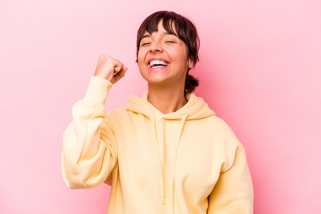 Junge hispanische Frau isoliert auf rosafarbenem Hintergrund, die einen Sieg, Leidenschaft und Begeisterung, glücklichen Ausdruck feiert