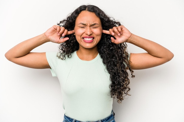 Junge hispanische Frau isoliert auf weißem Hintergrund, die Ohren mit Fingern bedeckt, gestresst und verzweifelt durch eine laute Umgebung