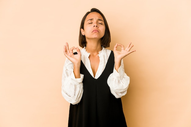 Junge hispanische Frau isoliert entspannt nach hartem Arbeitstag, sie führt Yoga durch.