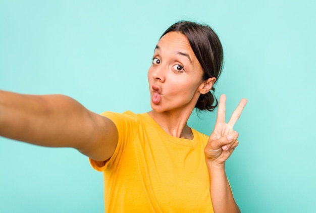 Junge hispanische Frau macht ein Selfie isoliert auf blauem Hintergrund