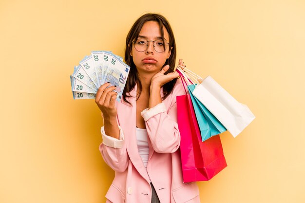 Junge hispanische Frau mit Einkaufstasche isoliert auf gelbem Hintergrund