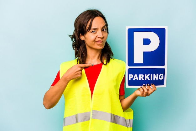 Junge hispanische Frau mit Parkschild isoliert auf blauem Hintergrund