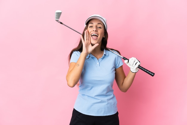 Junge hispanische Frau über isoliertem rosa Hintergrund, die Golf spielt und mit weit geöffnetem Mund schreit