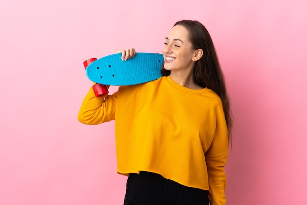 Junge hispanische Frau über isolierter rosa Wand mit einem Schlittschuh