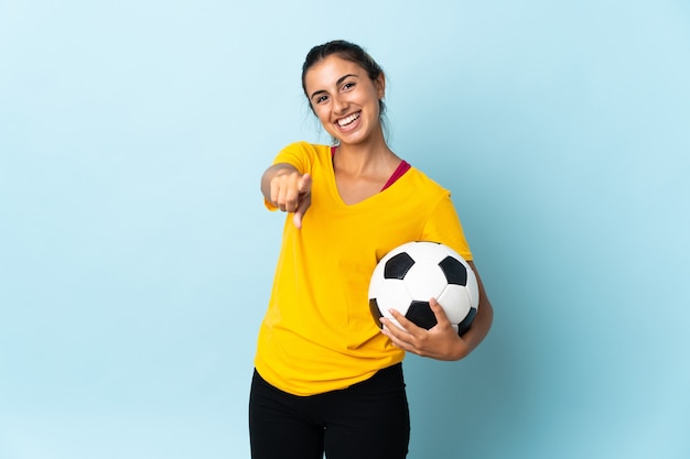 Junge hispanische Fußballspielerfrau über lokalisiert auf blauer Wand, die Front mit glücklichem Ausdruck zeigt