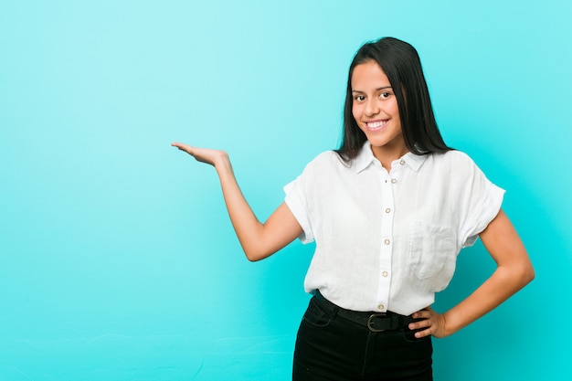 Junge hispanische kühle Frau gegen eine blaue Wand, die einen Raum zeigt