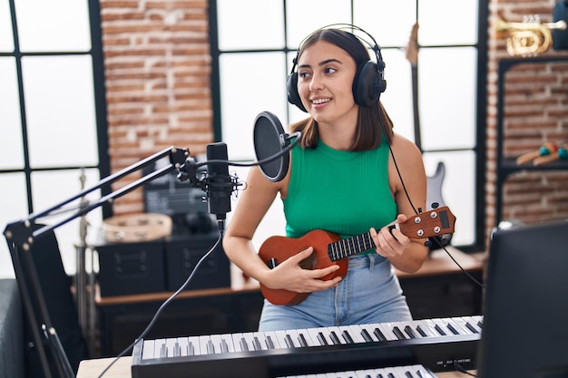 Junge hispanische Musikerin singt ein Lied und spielt Ukelele im Musikstudio