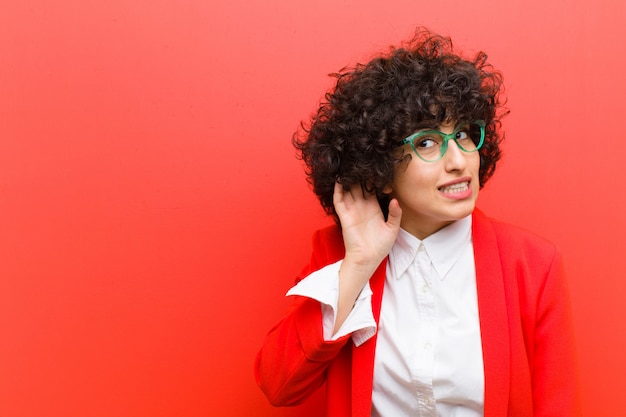 Junge hübsche Afrofrau, die ernst und neugierig schaut, hörend und versuchen, ein geheimes Gespräch oder einen Klatsch zu hören und lauschen