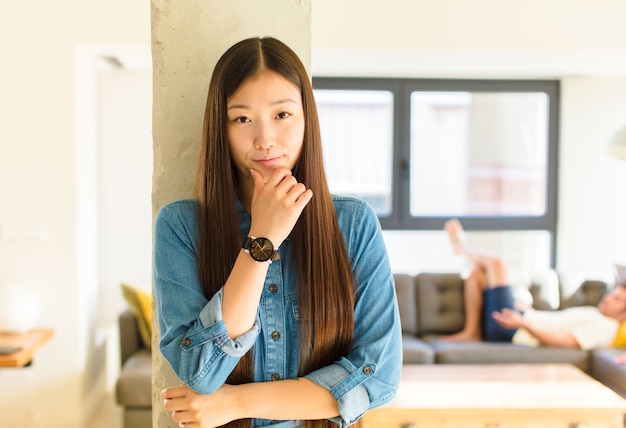 Junge hübsche asiatische Frau, die ein T-Shirt drinnen trägt