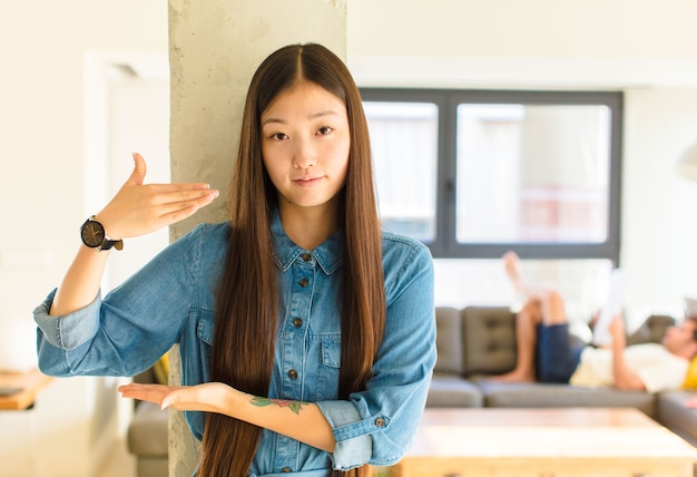 Junge hübsche asiatische Frau, die ein T-Shirt drinnen trägt