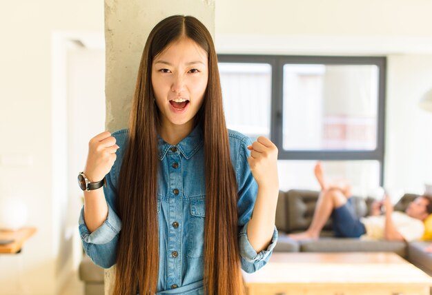 Junge hübsche asiatische Frau, die ein T-Shirt drinnen trägt