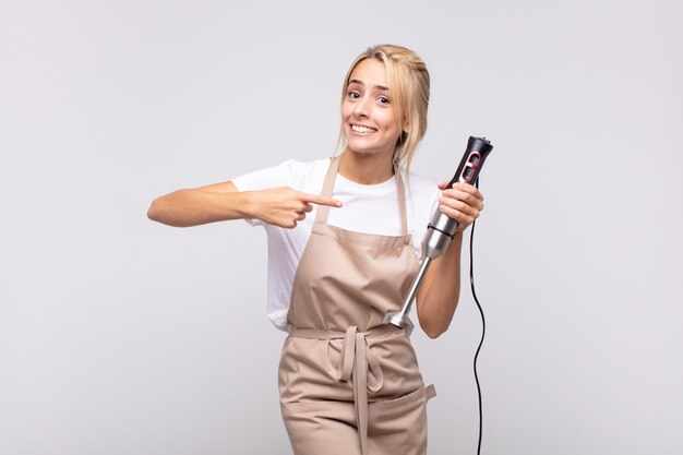 Junge hübsche blonde Bäckerin mit einem Mixer