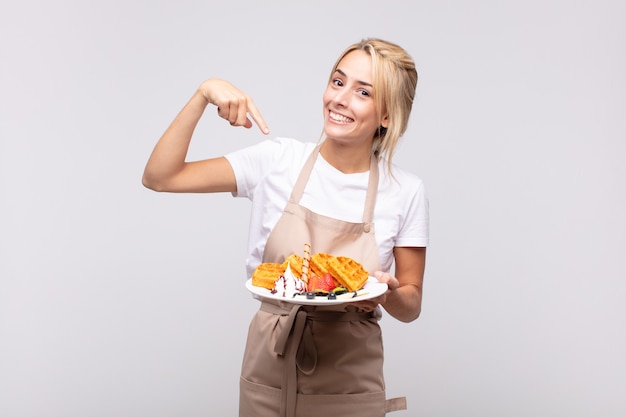 junge hübsche blonde Bäckerin. Waffelkonzept