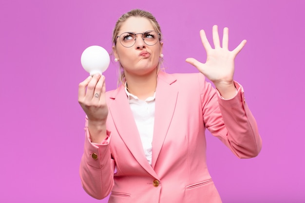 Junge hübsche blonde Frau, die eine Idee mit einer Glühbirne hat