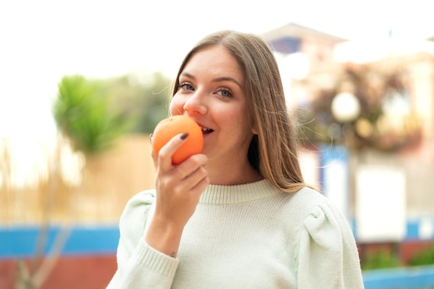 Junge hübsche blonde Frau, die eine Orange hält