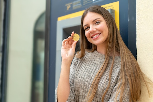 Foto junge hübsche blonde frau, die einen geldautomaten verwendet