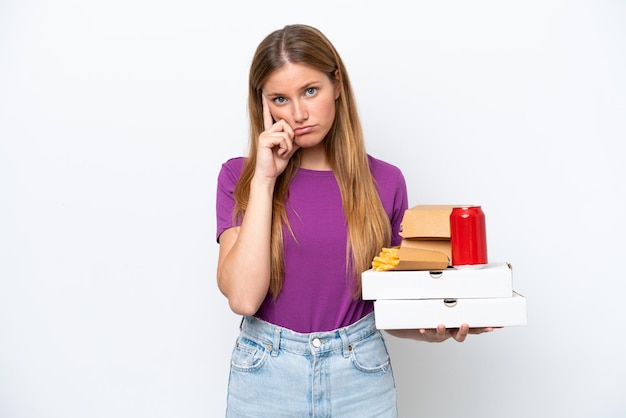 Junge hübsche blonde Frau, die Fast Food isoliert auf weißem Hintergrund hält und eine Idee denkt