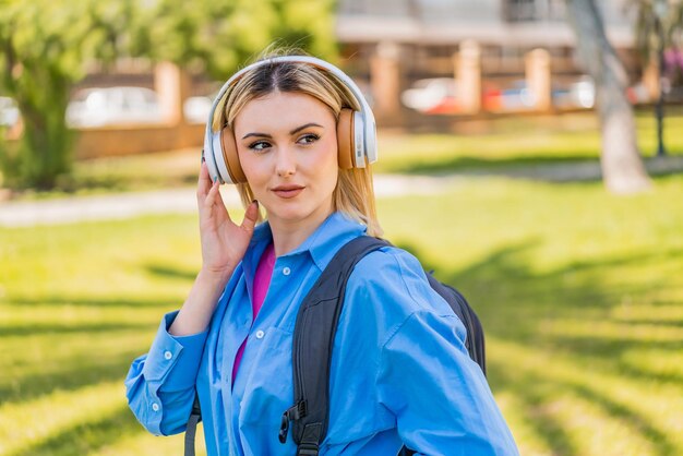 Foto junge hübsche blonde frau im freien, die musik hört