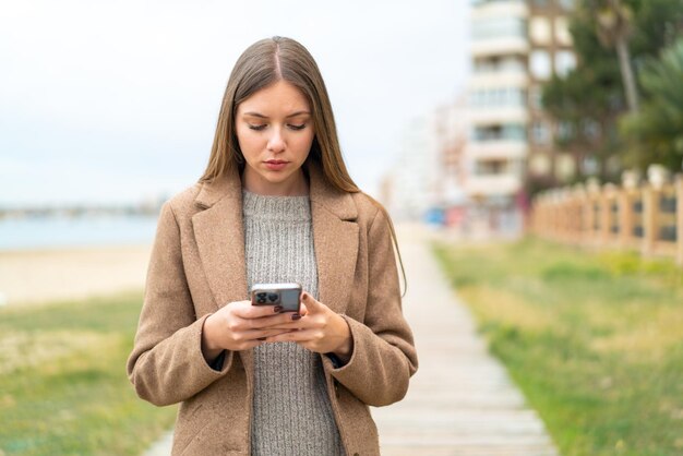 Junge hübsche Blondine, die Handy verwendet