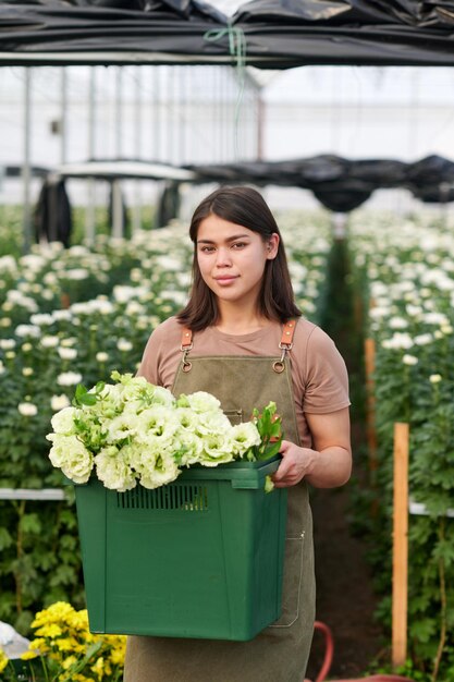 Junge hübsche Blumenhändlerin oder Mitarbeiterin eines Gartenzentrums, die Blumen hält