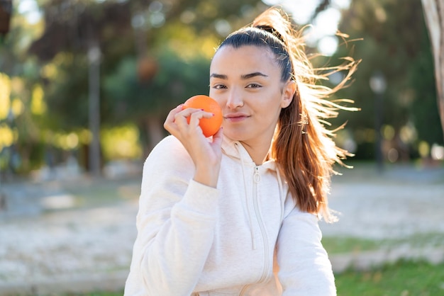 Junge hübsche brünette Frau hält eine Orange