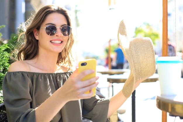 Junge hübsche brünette Frau im Freien in der Sommerstadt machen ein Selfie mit dem Handy.