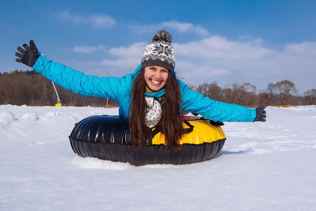 Junge hübsche Frau beim Snowtubing-Aufstieg Hände hochrutschen vom Schneehügel