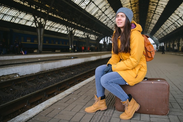 Junge hübsche Frau, die am Bahnhof auf den Zug wartet. sitzen auf
