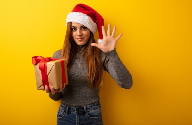 Junge hübsche Frau, die das Geschenk zeigt Nr. Fünf hält