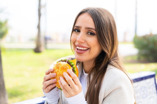 Junge hübsche Frau, die draußen einen Burger hält