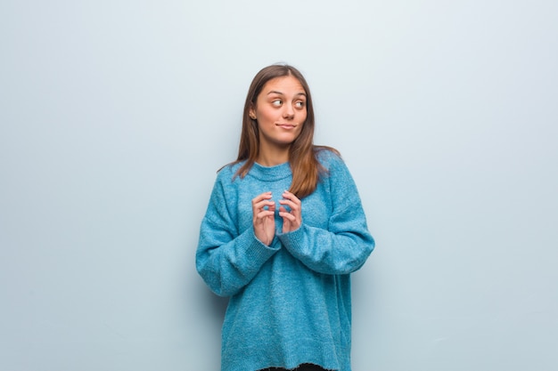 Junge hübsche Frau, die eine blaue Strickjacke ausarbeitet einen Plan trägt