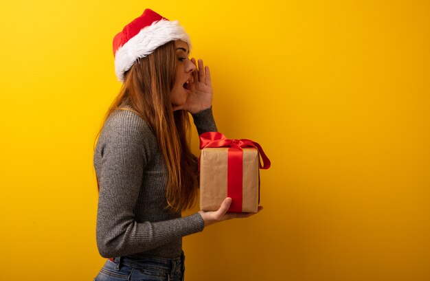 Junge hübsche Frau, die Geschenkflüsternden Klatschunterton hält