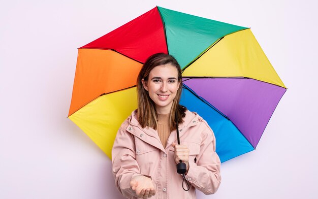 Junge hübsche Frau, die glücklich mit freundlichem Lächeln lächelt und ein Konzept anbietet und zeigt. Regenschirm-Konzept