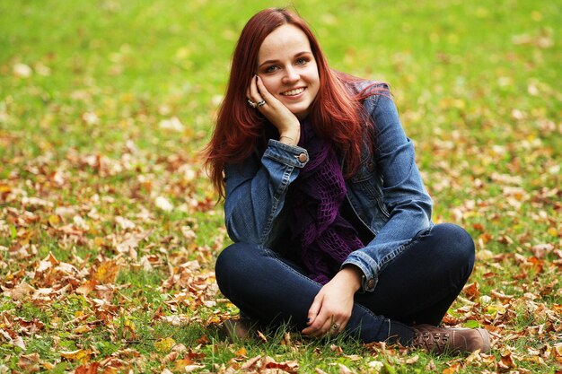 Junge hübsche Frau, die im Herbstpark sich entspannt