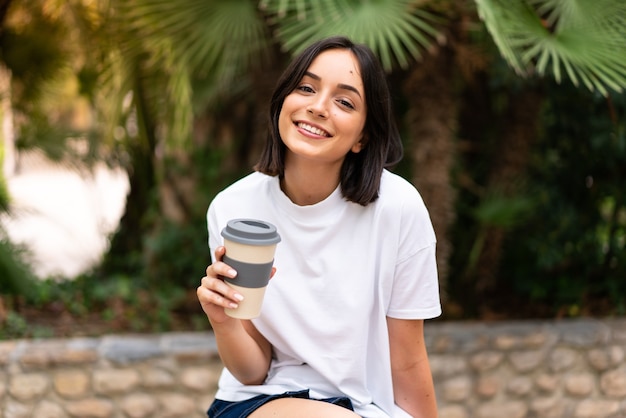 Junge hübsche Frau, die Kaffee hält, um im Freien wegzunehmen