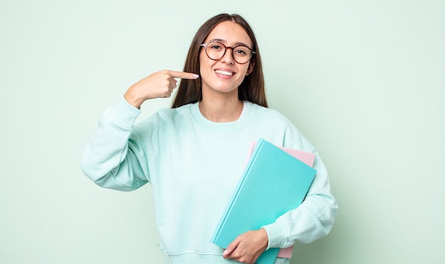 Junge hübsche Frau, die selbstbewusst lächelt und auf ein breites Lächeln zeigt. Universitätsstudent