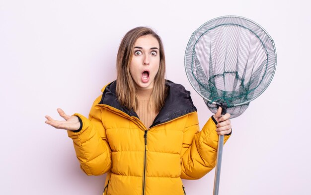 Foto junge hübsche frau, die sich extrem schockiert und überrascht fühlt. fischerkonzept