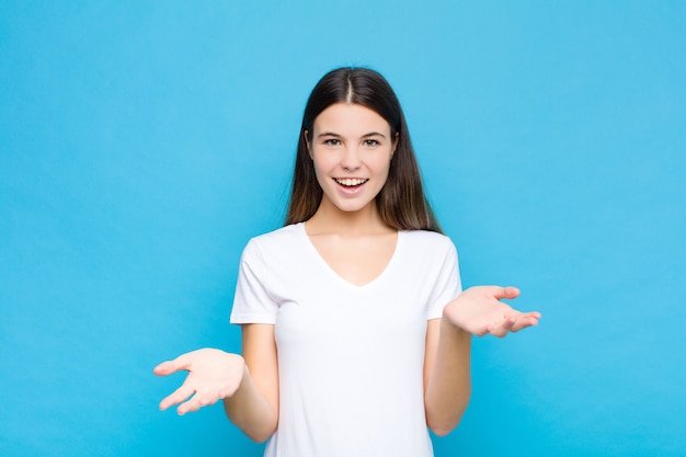 Junge hübsche Frau, die sich glücklich, erstaunt, glücklich und überrascht fühlt, als würde sie Omg ernsthaft sagen? Unglaublich gegen blaue Wand