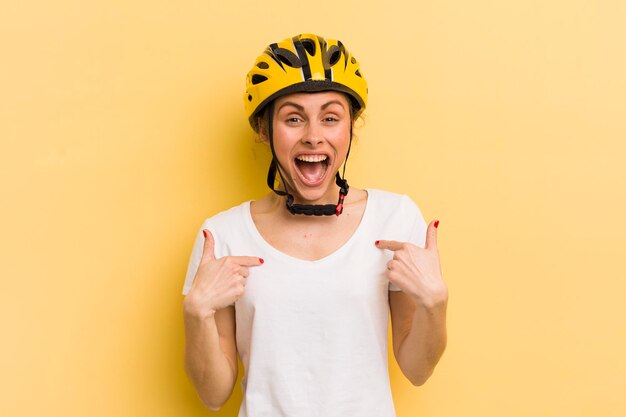 Junge hübsche Frau, die sich glücklich fühlt und mit einem aufgeregten Fahrradkonzept auf sich selbst zeigt