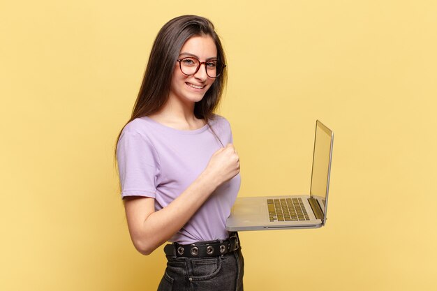 Junge hübsche Frau, die sich glücklich, positiv und erfolgreich fühlt, motiviert, wenn sie sich einer Herausforderung stellt oder gute Ergebnisse feiert. Laptop-Konzept