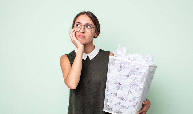 Junge hübsche frau, die sich nach einem ermüdenden gelangweilt, frustriert und schläfrig fühlt. Papierkugeln Müllkonzept