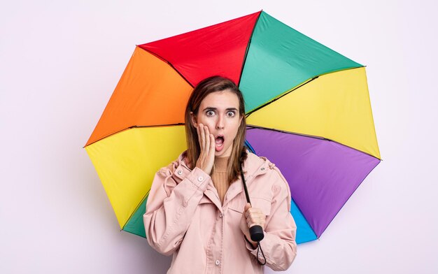 Foto junge hübsche frau, die sich schockiert und verängstigt fühlt. regenschirmkonzept