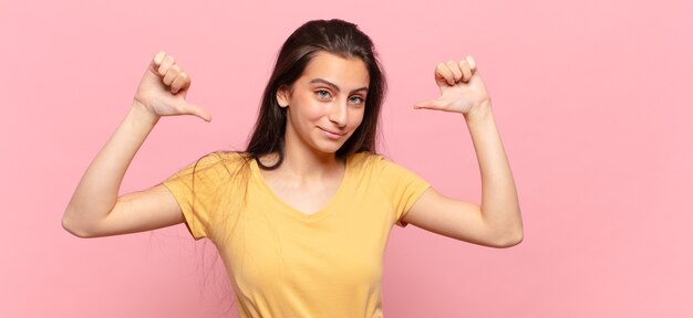 Junge hübsche Frau, die stolz, arrogant und selbstbewusst fühlt, zufrieden und erfolgreich aussieht und auf sich selbst zeigt