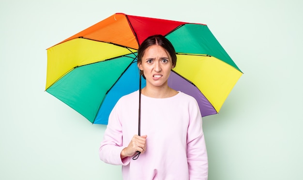 junge hübsche frau, die verwirrt und verwirrt aussieht. Regenschirmkonzept