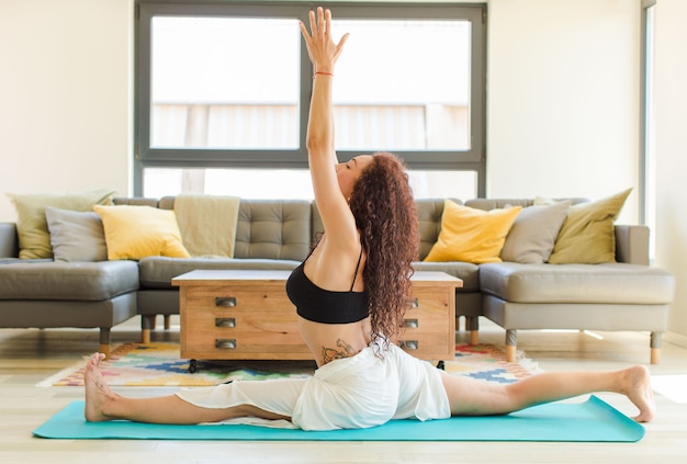 Junge hübsche Frau, die Yoga drinnen praktiziert