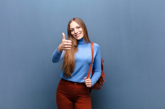 Junge hübsche Frau gegen blaue Wand mit einem Kopienraum