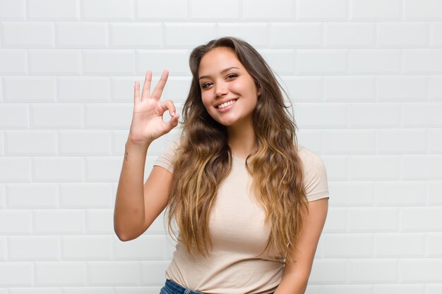 junge hübsche Frau gegen weiße Wand